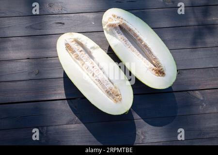 Zwei Hälften einer Melone auf einem Holztisch, Melonensamen in der Mitte. Stockfoto