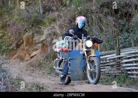 200218 -- NANCHANG, 18. Februar 2020 -- Luo Changshi, der Schulleiter der Xinzhu Grundschule, fährt mit seinem Motorrad, um kopierte Online-Kursmaterialien und Lehrbücher für Schüler auf einem Bergpfad im Dorf Xinzhu im Wanzai County, Provinz Jiangxi, zu liefern, 18. Februar 2020. China hat das Frühjahrssemester aufgrund des Coronavirus-Ausbruchs verschoben, der bis Sonntag landesweit über 70.000 Menschen infiziert hat. Millionen von Schülern, die zu Hause blieben, wandten sich mit Beginn der Schulzeit dem Online-Lernen zu. Die Provinz Jiangxi hat seit dem 10. Februar Online-Kurse für Studenten in der Provinz Jiangxi begonnen Stockfoto