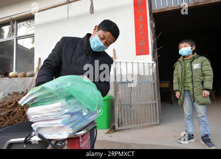 200218 -- NANCHANG, 18. Februar 2020 -- Luo Changshi L, der Schulleiter der Xinzhu Elementary School, liefert kopierte Online-Kurse und neue Semesterlehrbücher für Schüler Guo Shiqian im Dorf Xinzhu im Wanzai County, Provinz Jiangxi, 17. Februar 2020. China hat das Frühjahrssemester aufgrund des Coronavirus-Ausbruchs verschoben, der bis Sonntag landesweit über 70.000 Menschen infiziert hat. Millionen von Schülern, die zu Hause blieben, wandten sich mit Beginn der Schulzeit dem Online-Lernen zu. Die Provinz Jiangxi hat seit dem 10. Februar Online-Kurse für Studenten unter dem neuen Coronavir begonnen Stockfoto