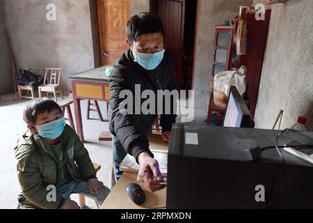 200218 -- NANCHANG, 18. Februar 2020 -- Luo Changshi R, der Schulleiter der Xinzhu Grundschule, lädt Online-Kurse für Schüler Guo Shiqian im Dorf Xinzhu im Wanzai County, ostchinesische Provinz Jiangxi, 17. Februar 2020 herunter. China hat das Frühjahrssemester aufgrund des Coronavirus-Ausbruchs verschoben, der bis Sonntag landesweit über 70.000 Menschen infiziert hat. Millionen von Schülern, die zu Hause blieben, wandten sich mit Beginn der Schulzeit dem Online-Lernen zu. Die Provinz Jiangxi hat seit dem 10. Februar Online-Kurse für Studenten im Zusammenhang mit dem neuartigen Coronavirus-Ausbruch begonnen. Luo Changshi, der HE Stockfoto