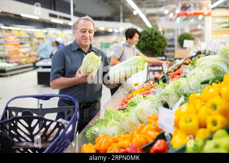 Reife Kunden wählen savoy Cabbage mit Interesse an der Lebensmittelabteilung des Supermarktes Stockfoto