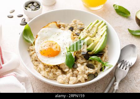 Herzhaftes Hafermehl mit frittiertem, sonnigem Side-up-Ei, Avocado und Kürbiskernen für ein gesundes Frühstück Stockfoto