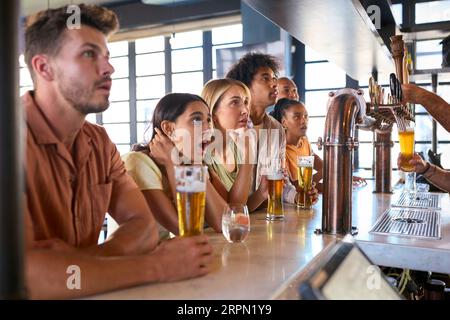 Enttäuschte Multi-kulturelle Gruppe von Freunden in der Sports Bar, die Team Lose Game im Fernsehen beobachtet Stockfoto