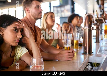 Enttäuschte Multi-kulturelle Gruppe von Freunden in der Sports Bar, die Team Lose Game im Fernsehen beobachtet Stockfoto