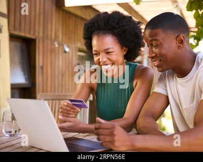Begeisterte Paare Mit Kreditkarte Mit Laptop Zu Hause, Um Urlaub Zu Buchen Oder Online Einzukaufen Stockfoto
