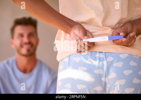 Frau Im Schlafzimmer Versteckt Positiven Schwangerschaftstest Hinter Dem Überraschungspartner Stockfoto