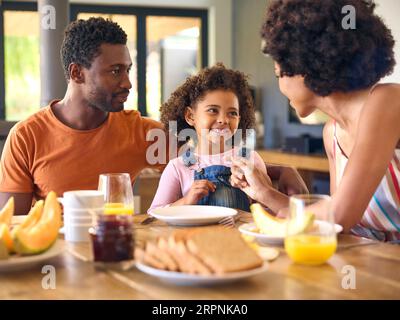 Familienschoß Mit Eltern Und Tochter Zu Hause Beim Gemeinsamen Frühstück Am Tisch Stockfoto