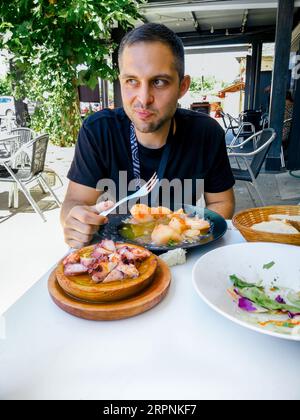 Junger Mann essen Pulpo a la Gallega mit Kartoffeln. Galizische octopus Gerichte. Bekannte Gerichte aus Galizien, Spanien. Stockfoto