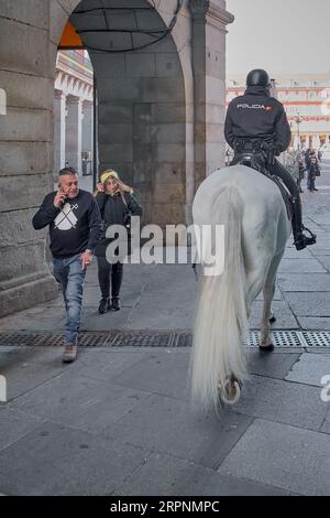 Polizistin zu Pferd, die Menschen auf dem Weg zum Platz Puerta del Sol in Madrid beobachtet und hilft. Stockfoto