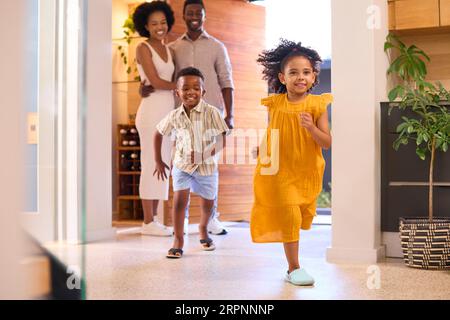 Familie, Die Nach Hause Kommt, Öffnet Die Vordertür Und Kinder Laufen Hinein Stockfoto