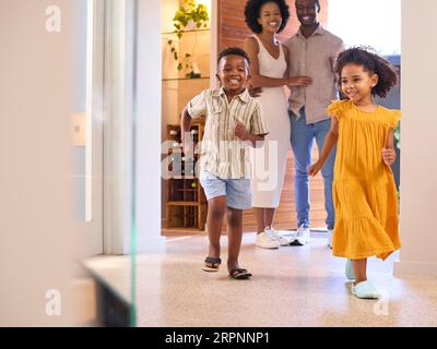 Familie, Die Nach Hause Kommt, Öffnet Die Vordertür Und Kinder Laufen Hinein Stockfoto