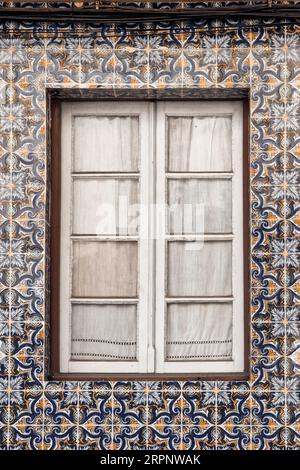 Nahaufnahme des alten portugiesischen Fensters mit traditionellen Azulejo-Keramikfliesen an der Wand Stockfoto