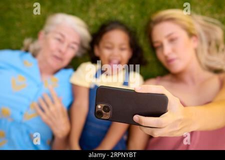 Overhead-Aufnahme Von Multi-Generation Female Family Living On Grass Mit Selfie Auf Dem Handy Stockfoto