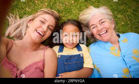 POV Overhead Shot von Multi-Generation Female Family Living on Grass Taking Selfie on Mobile Phone Stockfoto