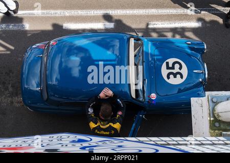 Der Fahrer lehnte sich an einer 1950er Austin A35 in der Boxengasse an einem Testtag für Revival auf der Goodwood Motor Racing Circuit in Chichester, West Sussex, Großbritannien Stockfoto