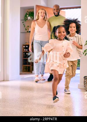 Familie, Die Nach Hause Kommt, Öffnet Die Vordertür Und Kinder Laufen Hinein Stockfoto