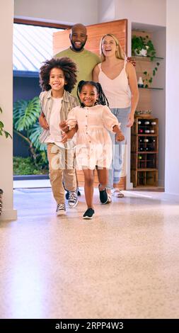 Familie, Die Nach Hause Kommt, Öffnet Die Vordertür Und Kinder Laufen Hinein Stockfoto