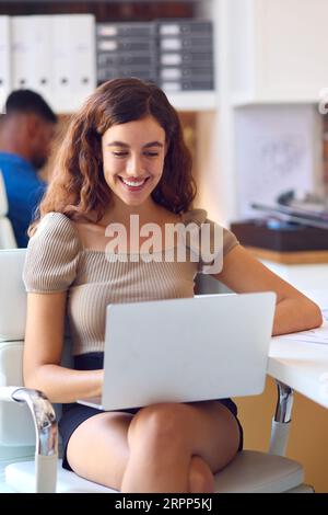 Junge Lächelnde Geschäftsfrau, Die Am Schreibtisch Im Büro Auf Laptop Arbeitet Stockfoto