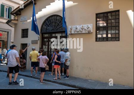Eine kleine geführte Gruppe von Touristen schaut durch die Fenster der La Bottega del Opera Di Santa Maria del Fiore (die Werkstatt oder das Studio von der Oper von Stockfoto