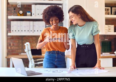 Zwei Junge Architektinnen Treffen Sich Und Machen Sich Ein Bild Von Bauplänen Auf Dem Mobiltelefon Stockfoto