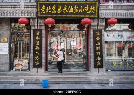 200313 -- PEKING, 13. März 2020 -- Ein Arbeiter reinigt die Tür eines Geschäfts in der Qianmen Straße in Peking, Hauptstadt von China, 13. März 2020. CHINA-PEKING-ALLTAG CN PengxZiyang PUBLICATIONxNOTxINxCHN Stockfoto