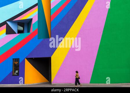 Woman spaziert im September in Eastbourne, East Sussex, UK, vorbei an der Towner Art Gallery mit farbenfrohen Dance Diagonal-Kunstwerken des deutschen Künstlers Lothar Götz Stockfoto