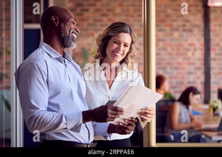 Geschäftskollegen Mit Digitalem Tablet Und Dokumenten Treffen Sich Im Geschäftigen Büro Stockfoto