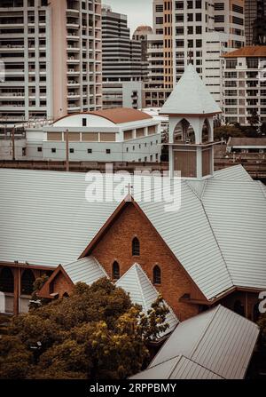 Bangkok, Thailand - 16. Juli 2023 - die christliche Kirche ist umgeben von modernen architektonischen Außengebäuden. Selektiver Fokus. Stockfoto