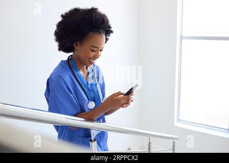 Ärztin Oder Krankenschwester, Die Auf Dem Handy Auf Treppen Im Krankenhaus Stöbern Stockfoto