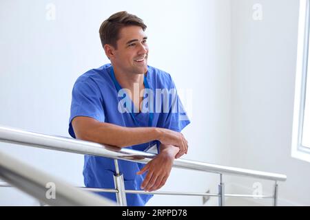 Porträt Des Lächelnden Jungen Männlichen Arztes Oder Der Krankenschwester, Die Auf Treppen Im Krankenhaus Steht Stockfoto