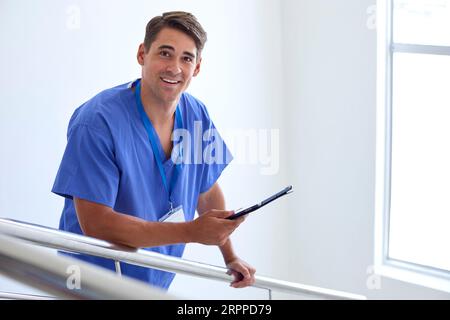 Porträt Des Männlichen Arztes Oder Der Krankenschwester Mit Digitalem Tablet, Das Patientennotizen Auf Treppen Im Krankenhaus Überprüft Stockfoto