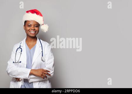 Glücklicher lächelnder Arzt in rotem Weihnachtsmannhut auf weißem Hintergrund Stockfoto