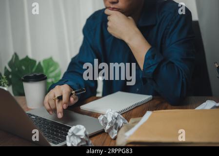 Mann, der von geschäftlicher Angst und Unzufriedenheit von der Arbeit gestresst wird. Geschäftsleute, die einen Computer mit Laptop auf dem Schreibtisch nutzen. Stockfoto