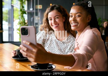 Zwei Junge Freundinnen Treffen Sich Im Coffee Shop Und Posieren Für Selfie Stockfoto