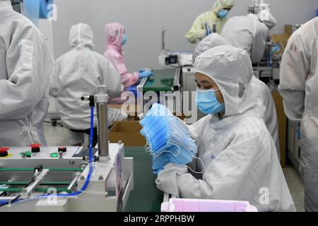 200318 -- SHENZHEN, 18. März 2020 -- Mitarbeiter stellen Masken in der Werkstatt zur Herstellung von Masken von Foxconn in Shenzhen, Provinz Guangdong in Südchina, 17. März 2020 her. In Shenzhen sind mehr als 97 Prozent der Industrieunternehmen über der ausgewiesenen Größe, und die wichtigsten Projekte werden wieder in Betrieb genommen. CHINA-GUANGDONG-SHENZHEN-WIEDERAUFNAHME DER PRODUKTION CN LIANGXXU PUBLICATIONXNOTXINXCHN Stockfoto