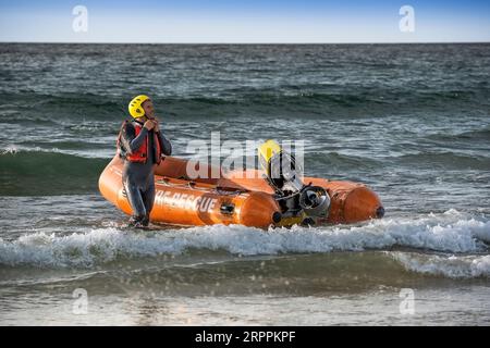 Mitglieder des Newquay Surf Life Saving Club bereiten sich darauf vor, ein Küstenrettungsboot der Arancia-Klasse für eine Trainingseinheit im Fistral in Newquay in C zu starten Stockfoto