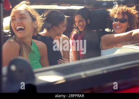 Blick Durch Die Windschutzscheibe Der Gruppe Lachender Weiblicher Freunde, Die Spaß Im Open Top Car Auf Road Trip Haben Stockfoto