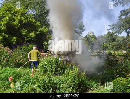 London, Großbritannien. September 2023. Ein Mitarbeiter des Parks versucht, das Feuer zu löschen, das in einer Holzkonstruktion ausbrach, die Insekten im St. James's Park nahe der Rückseite der Downing Street beherbergt. Eine Person wurde wegen mutmaßlicher Brandstiftung inhaftiert. Quelle: Vuk Valcic/Alamy Live News Stockfoto