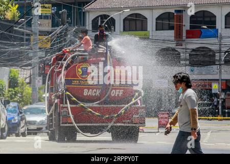 200323 -- QUEZON CITY, 23. März 2020 -- Feuerwehrmänner auf einem Feuerwehrspray Desinfektionsmittel auf einer Straße in Quezon City, Philippinen, 23. März 2020. Die Zahl der COVID-19-Fälle auf den Philippinen ist auf 462 gestiegen, sagte das Gesundheitsministerium des Landes am Montag. Das DOH sagte in einem Bericht, dass 33 Menschen an der hochinfektiösen Krankheit gestorben sind, während sich 18 erholt haben. PHILIPPINEN-COVID-19-MEASURES ROUELLExUMALI PUBLICATIONxNOTxINxCHN Stockfoto