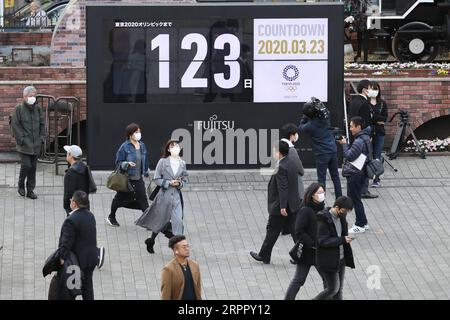 200323 -- TOKIO, 23. März 2020 -- Menschen laufen in der Nähe einer Tokio 2020 Olympische Spiele Countdown Anzeige im Shimbashi Bezirk, Tokio, Japan, 23. März 2020. Der japanische Premierminister Shinzo Abe teilte dem Parlament am Montag mit, dass die Olympischen Spiele in Tokio aufgrund der weltweiten Ausbreitung des Coronavirus verschoben werden könnten. SPJAPAN-TOKYO-OLYMPICS DuxXiaoyi PUBLICATIONxNOTxINxCHN Stockfoto