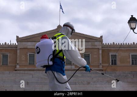 200324 -- ATHEN, 24. März 2020 -- ein Mitarbeiter der Gemeinde Athen sprüht Desinfektionsmittel auf dem Syntagma-Platz in Athen, Griechenland, 24. März 2020. Stadtstraßen in ganz Griechenland wurden verlassen, als die Regierung am Montag eine 14-tägige landesweite Sperrung einleitete, um die weitere Ausbreitung des neuen Coronavirus einzudämmen. Griechenland hat bisher 17 Todesfälle im Zusammenhang mit COVID-19 verzeichnet, gegenüber 15 Berichten am Tag zuvor und 71 neuen bestätigten Fällen, was die Gesamtzahl auf 695 erhöht, sagte Sotirios Tsiodras, Sprecher des Gesundheitsministeriums zur Epidemie, auf einer regelmäßigen Pressekonferenz am Montag. Foto von Stockfoto