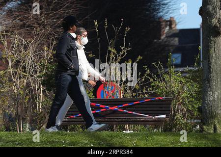 200325 -- BRÜSSEL, 25. März 2020 -- Menschen gehen an Bänken vorbei, die von der Polizei in einem Park in Brüssel, Belgien, am 25. März 2020 mit dem Absperrband gefesselt sind. Bänke in Parks wurden verboten, weil sie sitzen mussten, um zu verhindern, dass sich die Leute versammeln oder zu lange in den Parks bleiben. BELGIEN-BRÜSSEL-COVID-19-PARK-BANK ZhengxHuansong PUBLICATIONxNOTxINxCHN Stockfoto