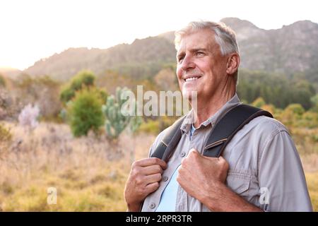 Porträt Eines Aktiven Seniorenmannes Mit Rucksack, Der Auf Einer Wanderung Auf Dem Land Unterwegs Ist Stockfoto