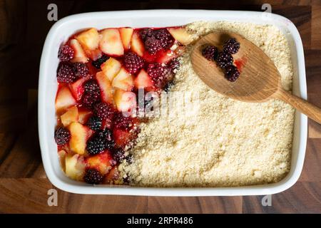 Ein hausgemachter traditioneller englischer Apfel- und brombeerbröckel. Der Kuchen wird aus lokal geernteten Wildfrüchten hergestellt und befindet sich in einer großen Keramikform Stockfoto