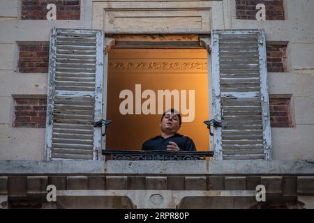 200329 -- PARIS, 29. März 2020 Xinhua -- der französische Tenor Stephane Senechal singt aus seinem Fenster für die Bewohner seiner Straße in Paris, Frankreich, 28. März 2020. Frankreich befindet sich in einem Lockdown, um die Ausbreitung der COVID-19-Pandemie einzudämmen. Foto von Aurelien Morissard/Xinhua FRANCE-PARIS-COVID-19-BALKON-MUSIKER PUBLICATIONxNOTxINxCHN Stockfoto