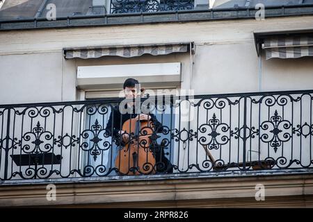 News Bilder des Tages 200329 -- PARIS, 29. März 2020 Xinhua -- Cellist Camilo Peralta spielt Cello auf seinem Balkon in Paris, Frankreich, 28. März 2020. Frankreich befindet sich in einem Lockdown, um die Ausbreitung der COVID-19-Pandemie einzudämmen. Foto von Aurelien Morissard/Xinhua FRANCE-PARIS-COVID-19-BALKON-MUSIKER PUBLICATIONxNOTxINxCHN Stockfoto