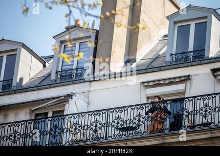 200329 -- PARIS, 29. März 2020 Xinhua -- Cellistin Camilo Peralta spielt das Cello auf seinem Balkon in Paris, Frankreich, 28. März 2020. Frankreich befindet sich in einem Lockdown, um die Ausbreitung der COVID-19-Pandemie einzudämmen. Foto von Aurelien Morissard/Xinhua FRANCE-PARIS-COVID-19-BALKON-MUSIKER PUBLICATIONxNOTxINxCHN Stockfoto