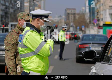 200331 -- BUKAREST, 31. März 2020 Xinhua -- Ein rumänischer Polizist und Ein Soldat überprüfen die Leute auf Papiere bezüglich ihrer Bewegungen in der Innenstadt von Bukarest, Rumänien, 30. März 2020. Rumänien kündigte eine landesweite Sperrung ab Mittwochmorgen an. Das Land trat am 16. März in den Ausnahmezustand ein, nachdem die Zahl der COVID-19-Fälle 100 überschritten hatte. Foto von Cristian Cristel/Xinhua ROMANIA-BUKAREST-COVID-19-CHECKING PUBLICATIONxNOTxINxCHN Stockfoto