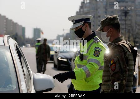 200331 -- BUKAREST, 31. März 2020 Xinhua -- Ein rumänischer Polizist und Ein Soldat überprüfen die Leute auf Papiere bezüglich ihrer Bewegungen in der Innenstadt von Bukarest, Rumänien, 30. März 2020. Rumänien kündigte eine landesweite Sperrung ab Mittwochmorgen an. Das Land trat am 16. März in den Ausnahmezustand ein, nachdem die Zahl der COVID-19-Fälle 100 überschritten hatte. Foto von Cristian Cristel/Xinhua ROMANIA-BUKAREST-COVID-19-CHECKING PUBLICATIONxNOTxINxCHN Stockfoto