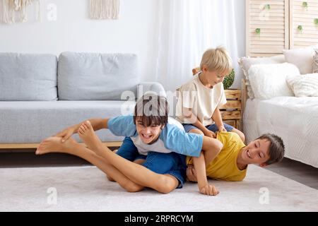 Glückliche positive Kinder, kitzeln auf den Füßen, haben Spaß zusammen, Junge Brüder zu Hause haben einen wunderbaren Tag der Freude zusammen Stockfoto